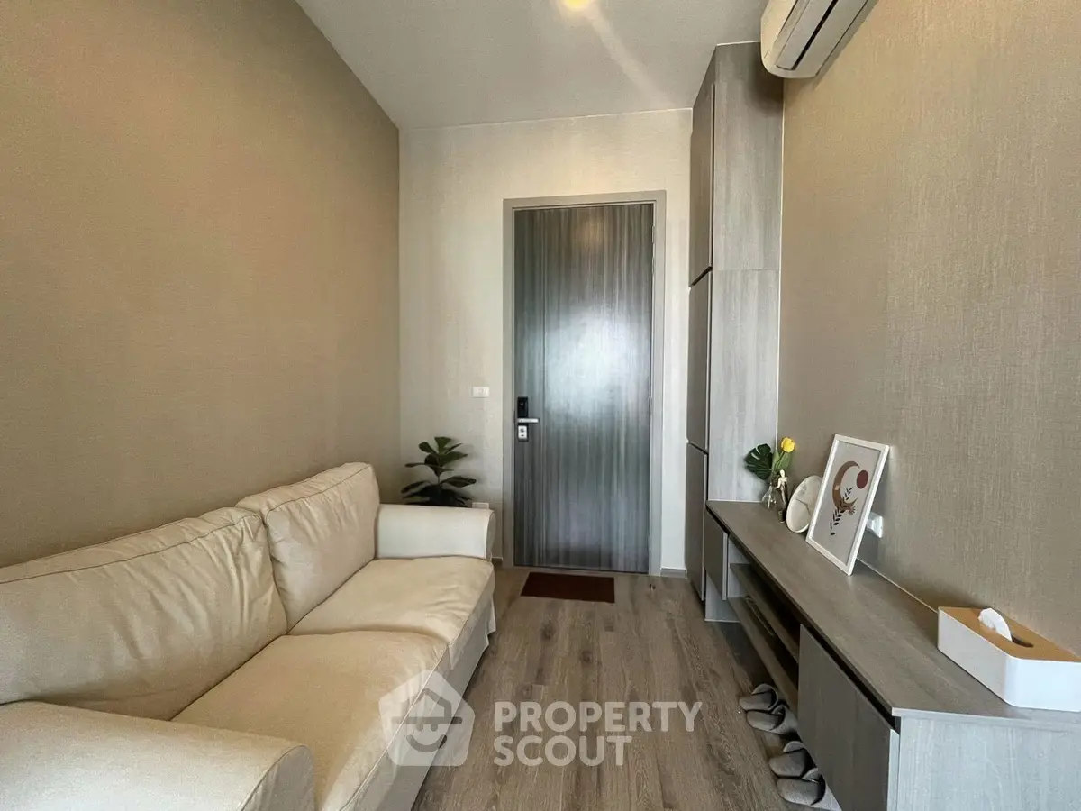 Cozy living room with modern decor and air conditioning, featuring a comfortable sofa and stylish wooden flooring.