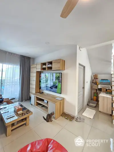 Modern living room with stylish wooden furniture and large TV, featuring cozy decor and natural light.