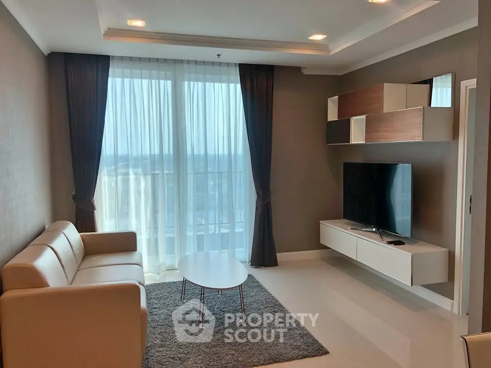 Modern living room with sleek furniture and large window offering city view.