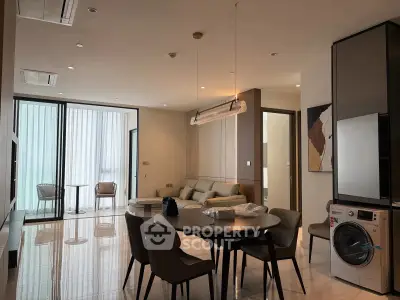 Modern living room with sleek furniture and integrated washer, featuring a cozy dining area and balcony access.
