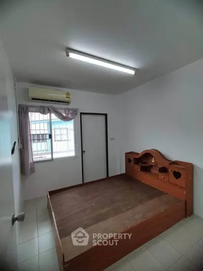 Cozy bedroom with wooden bed frame and natural light from window.