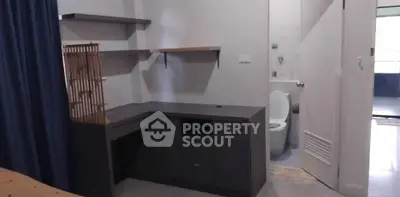 Cozy study nook with shelves and adjacent bathroom in modern apartment.