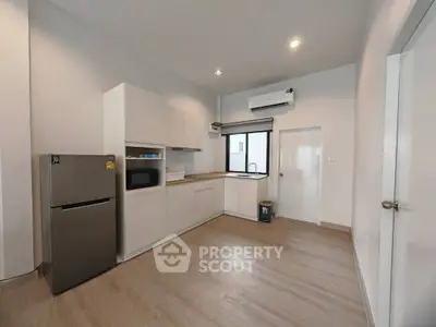 Modern kitchen with sleek cabinets, stainless steel fridge, and microwave in a bright, spacious layout.