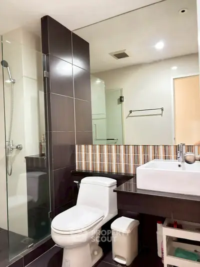 Modern bathroom with glass shower and stylish sink in contemporary apartment.