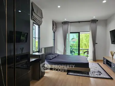 Spacious bedroom with modern decor and large windows overlooking greenery.