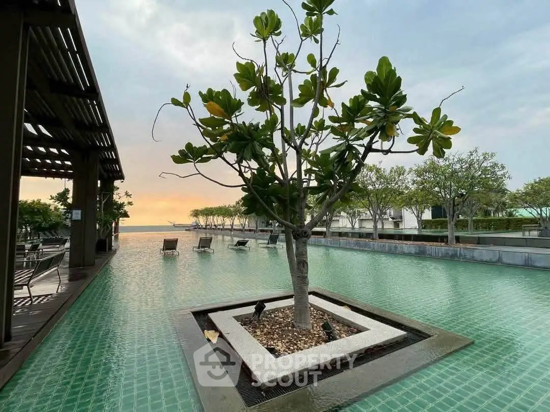 Luxurious poolside view with serene water and lush greenery at sunset, perfect for relaxation and leisure.