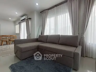 Spacious living room with modern gray sofa and elegant curtains