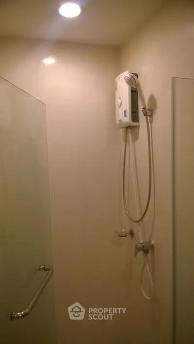 Modern bathroom with shower and water heater, featuring sleek design and bright lighting.