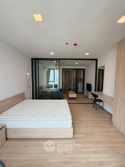 Spacious modern studio apartment with wooden flooring and glass partition.