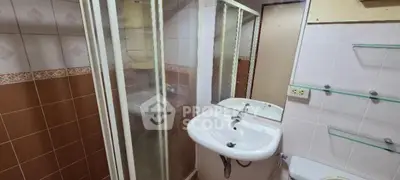 Compact bathroom with shower and sink in a cozy apartment.