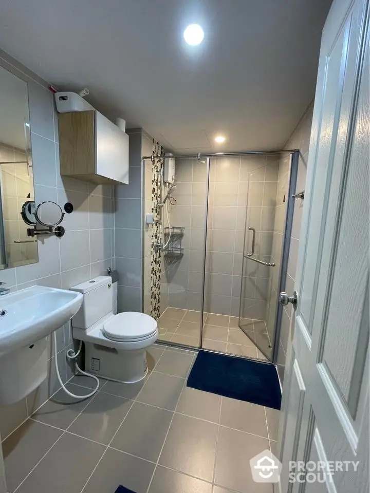 Modern bathroom with glass shower and sleek fixtures in contemporary home.