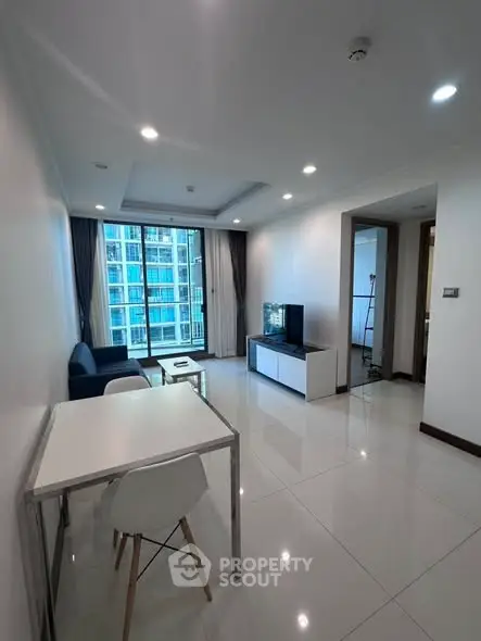 Modern living room with sleek furniture and large windows offering city views.