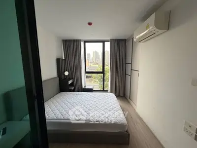 Modern bedroom with city view, featuring a large window and air conditioning.