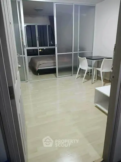 Cozy apartment with sliding glass doors leading to a bedroom, featuring a small dining area and modern decor.