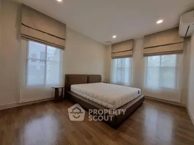 Spacious bedroom with large windows and modern decor, perfect for relaxation.