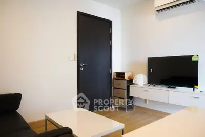 Modern living room with sleek furniture and wall-mounted TV, featuring minimalist design and air conditioning.