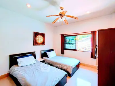 Spacious bedroom with twin beds and ceiling fan, perfect for comfort and relaxation.