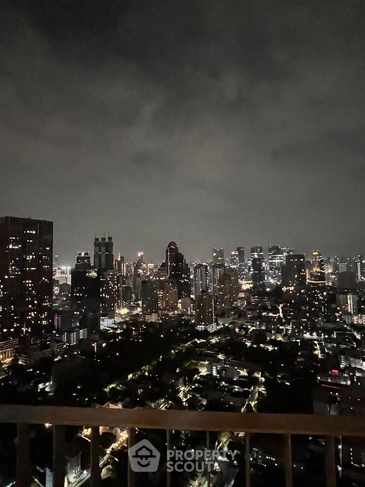 Stunning city skyline view from a high-rise balcony at night, showcasing vibrant urban lights.
