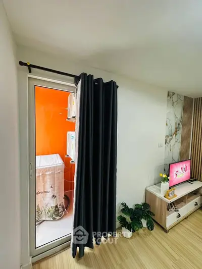 Modern living room with TV, stylish decor, and access to a bright balcony.