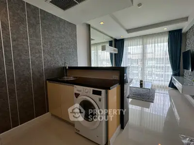 Modern living room with washing machine and stylish decor, featuring large windows and sleek finishes.