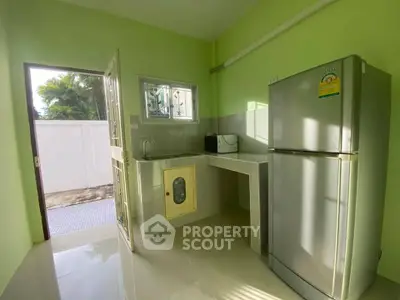 Charming kitchen with green walls and modern appliances, featuring a fridge and microwave.