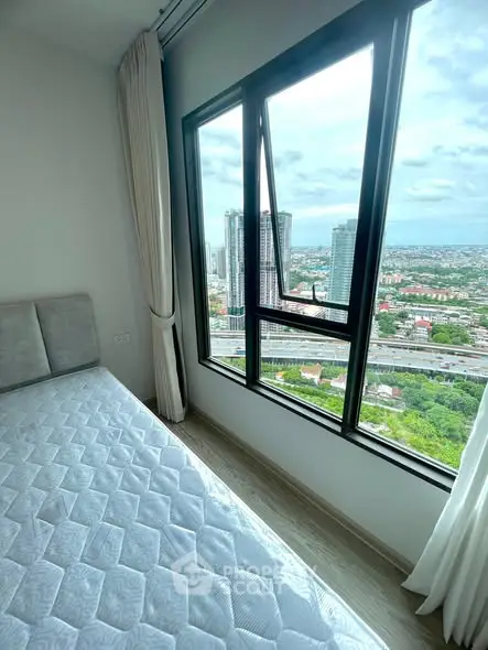 Stunning bedroom with panoramic city view from high-rise window, featuring a cozy bed and elegant curtains.