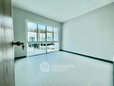 Spacious empty room with large window and modern flooring, perfect for customization.