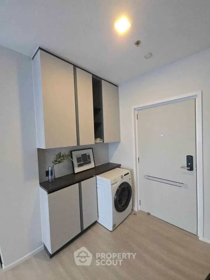 Modern laundry area with sleek cabinets and washing machine in a stylish apartment.