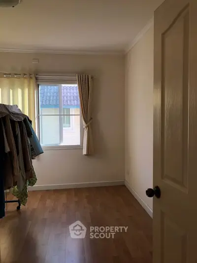Cozy room with wooden flooring and window view, perfect for a small bedroom or study.