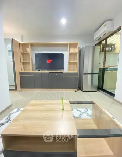 Modern living room with sleek furniture and large TV, featuring a stylish open layout and balcony access.