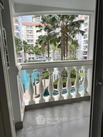 Charming balcony view overlooking lush gardens and a sparkling pool in a luxurious residential complex.