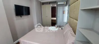 Modern bedroom with wall-mounted TV and spacious wardrobe in a stylish apartment.
