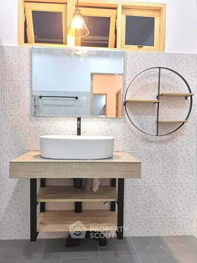 Modern bathroom with stylish vanity and round mirror, featuring elegant lighting and open shelving.