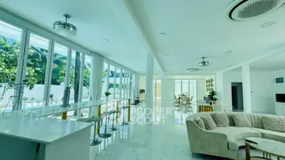 Luxurious open-plan living room with modern decor and expansive windows overlooking lush greenery.
