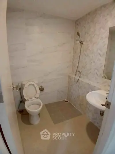 Modern bathroom with sleek design featuring a toilet, sink, and shower area with elegant tiling.
