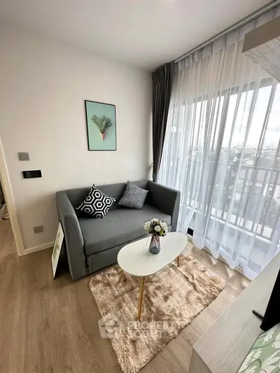 Chic living room with cozy sofa, stylish decor, and large window offering natural light and balcony view.