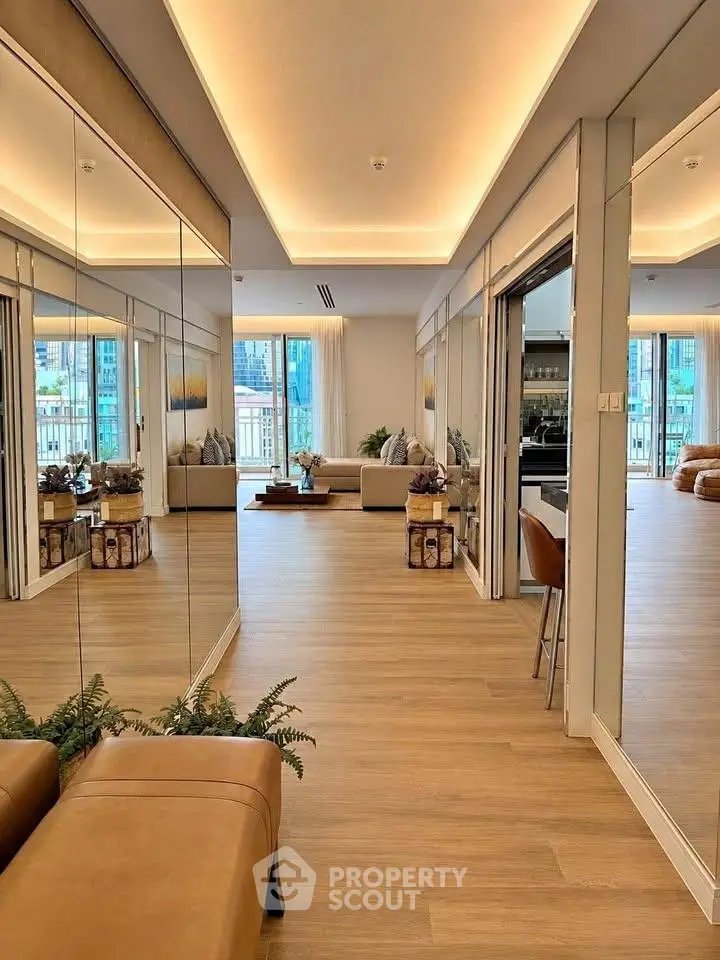 Luxurious modern living room with elegant decor and mirrored walls, featuring a spacious open layout and wooden flooring.