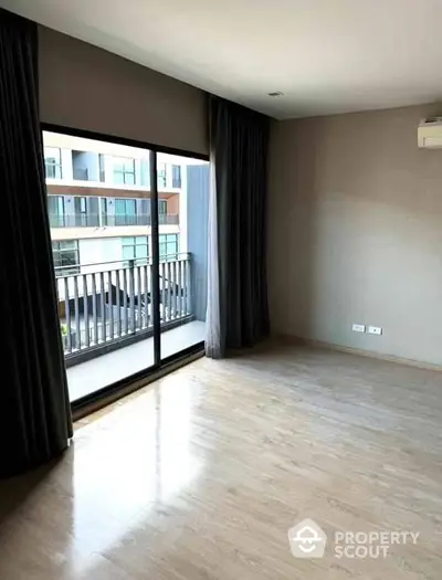 Spacious empty room with large window and balcony view in modern apartment.