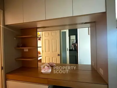Modern bedroom with built-in wooden vanity and mirror, showcasing sleek storage solutions.