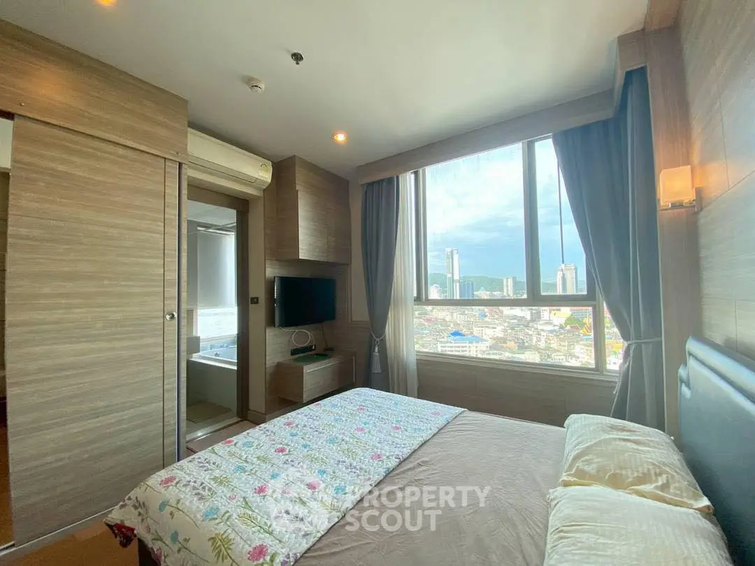 Modern bedroom with city view, featuring large window and stylish decor.
