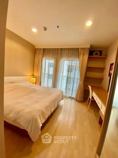 Spacious bedroom with large windows and elegant curtains in modern apartment.