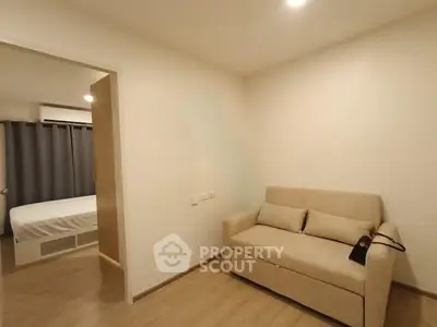 Cozy apartment interior with a small living area and bedroom view, featuring modern decor and neutral tones.