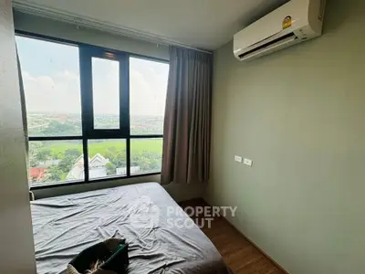 Cozy bedroom with large window offering scenic views and modern air conditioning unit.