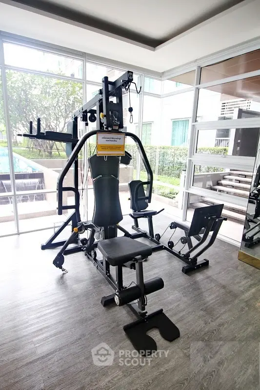 Modern gym with state-of-the-art equipment and large windows overlooking a garden view.