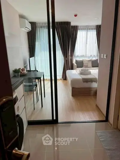 Modern studio apartment with glass partition, cozy bedroom, and stylish decor.