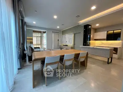 Spacious modern dining and kitchen area with elegant lighting and sleek furniture.
