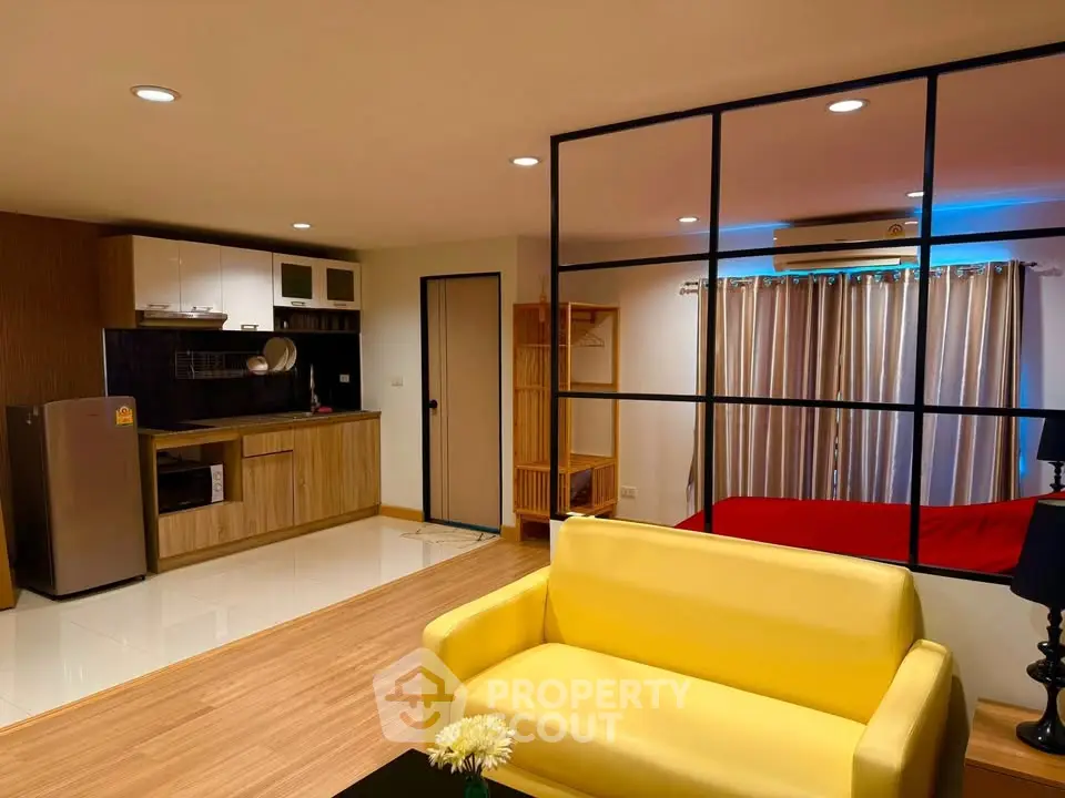 Modern open-plan living room with vibrant yellow sofa and sleek kitchen area.