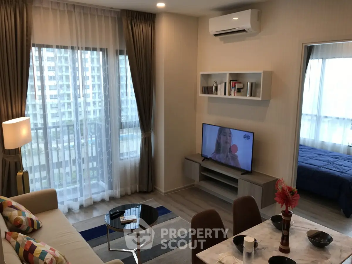 Modern living room with open layout, stylish decor, and large windows offering city views.