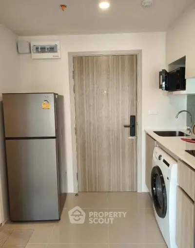 Modern kitchen with stainless steel fridge and washing machine in compact layout.