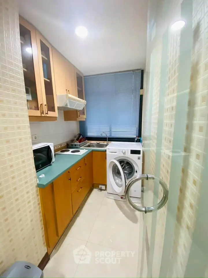 Compact kitchen with modern appliances and washing machine in cozy apartment